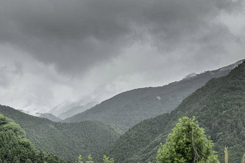 曇り空に連なる緑豊かな山脈の重層的風景