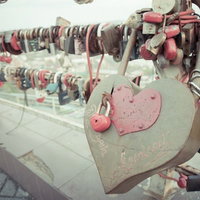橋に取り付けられた赤いハート形の南京錠、愛の誓いを示すペアロックの写真