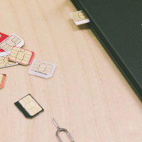 散らばったSIMカードとスマートフォン、通信機器の写真