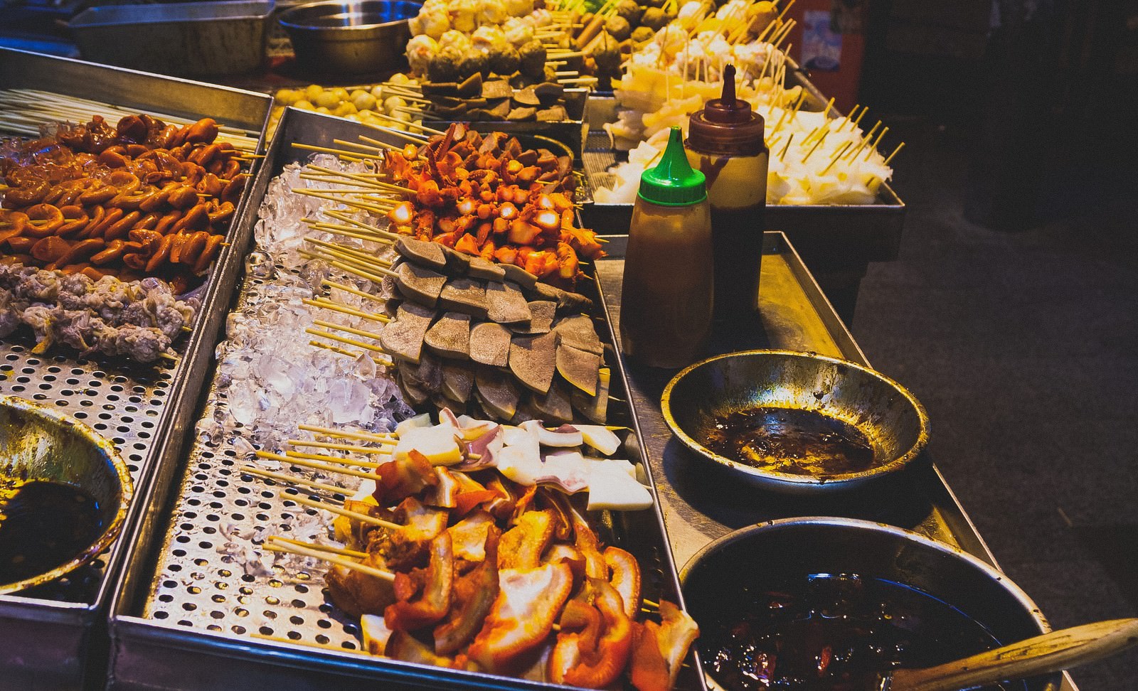 香港の屋台で焼き鳥やコーン、ソーセージなど串焼き食材がトレーに並んでいる