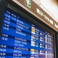 国際便第2ターミナルの青い電光掲示板でフライト情報を確認する乗客の写真