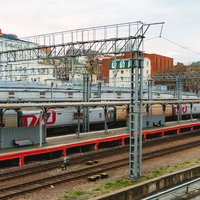 ウラジオストクの駅ホームに停車する赤いラインの電車の写真