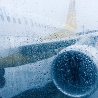 雨天の滑走路で待機する旅客機、台風などの悪天候時の空港運用の写真
