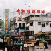 香港の場末にたたずむ赤い看板と老朽化した街並みの写真