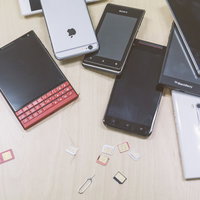 複数台の検証機（スマホ）と散らばるSIMカードの写真