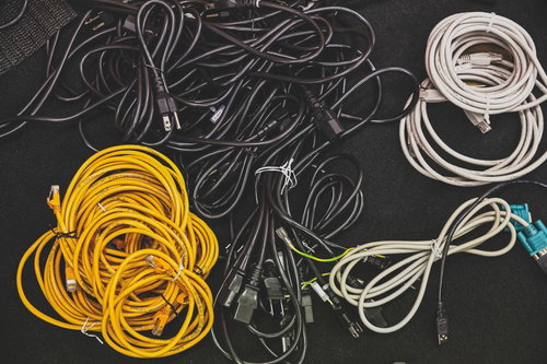 黒い布の上に黄色や白や青のケーブルが束ねられた接写