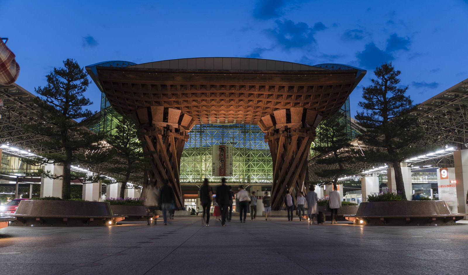 ライトアップされた金沢駅の鼓門の夜景。木製の円形建造物と金属格子窓が見える