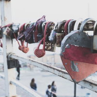 手すりに取り付けられたハート型の南京錠と赤い布の写真