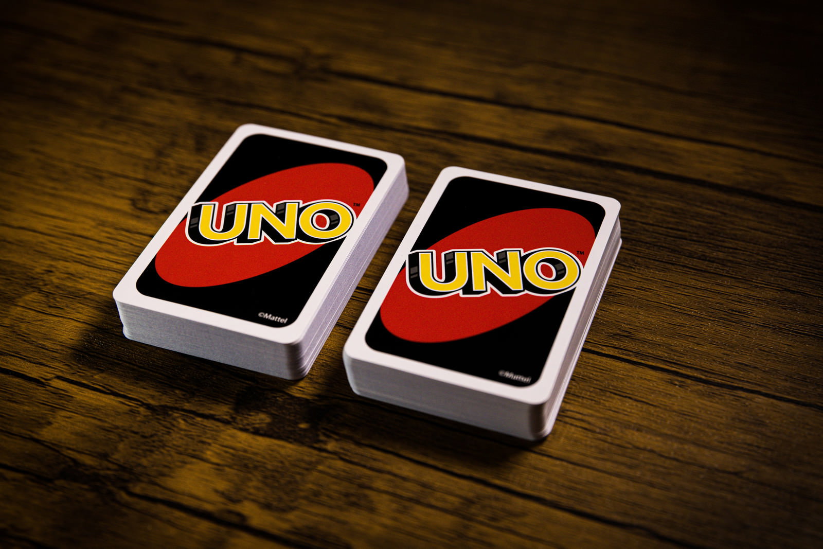 木製テーブルの上に置かれた2つのUNOカードの山札