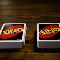 木目のテーブルに並ぶUNOの山札とカードゲームの風景の写真