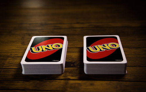 木目のテーブルに並ぶUNOの山札とカードゲームの風景