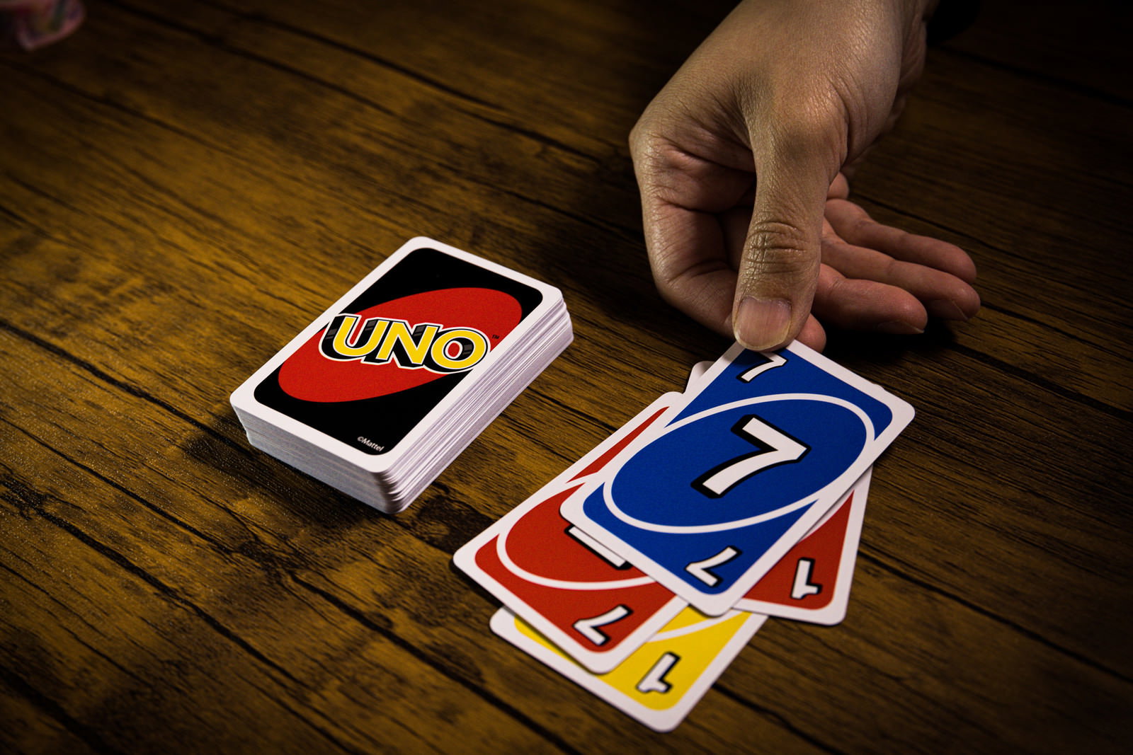 木目調のテーブルでUNOカードを出そうとする手の様子