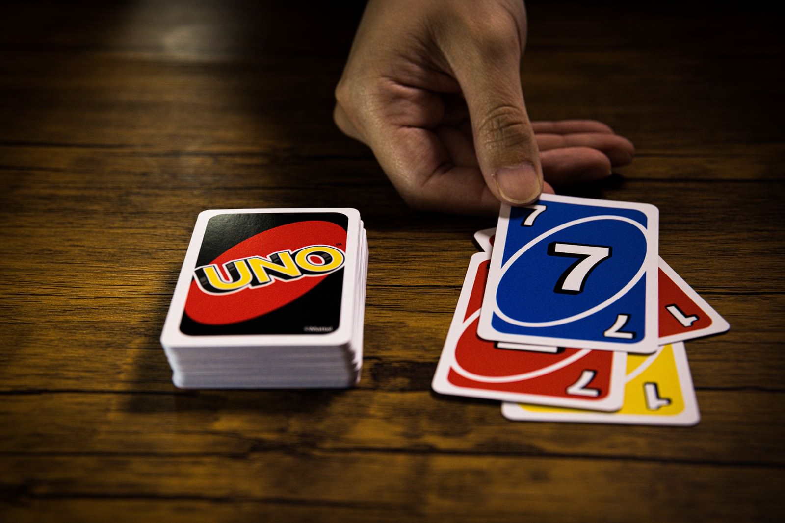 UNOで手札から赤い7のカードを出そうとする手と山札
