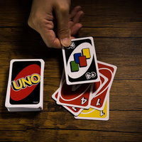 木製テーブルでUNOのワイルド ドロー4を場に出すの写真