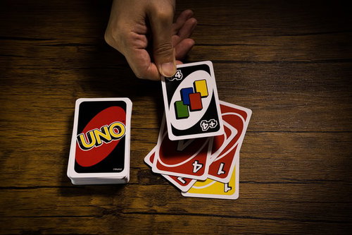 木製テーブルでUNOのワイルド ドロー4を場に出す