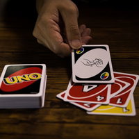 木製テーブルの上でUNOカードをシャッフルする手元の写真