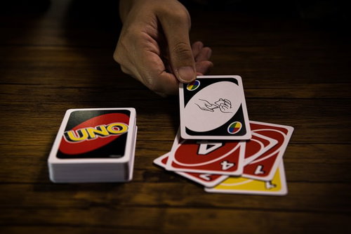木製テーブルの上でUNOカードをシャッフルする手元