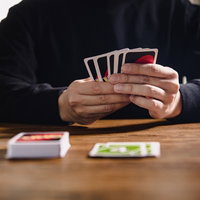 木製テーブルで手札を持つUNOのプレイヤーの写真