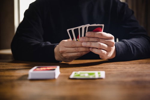 木製テーブルで手札を持つUNOのプレイヤー