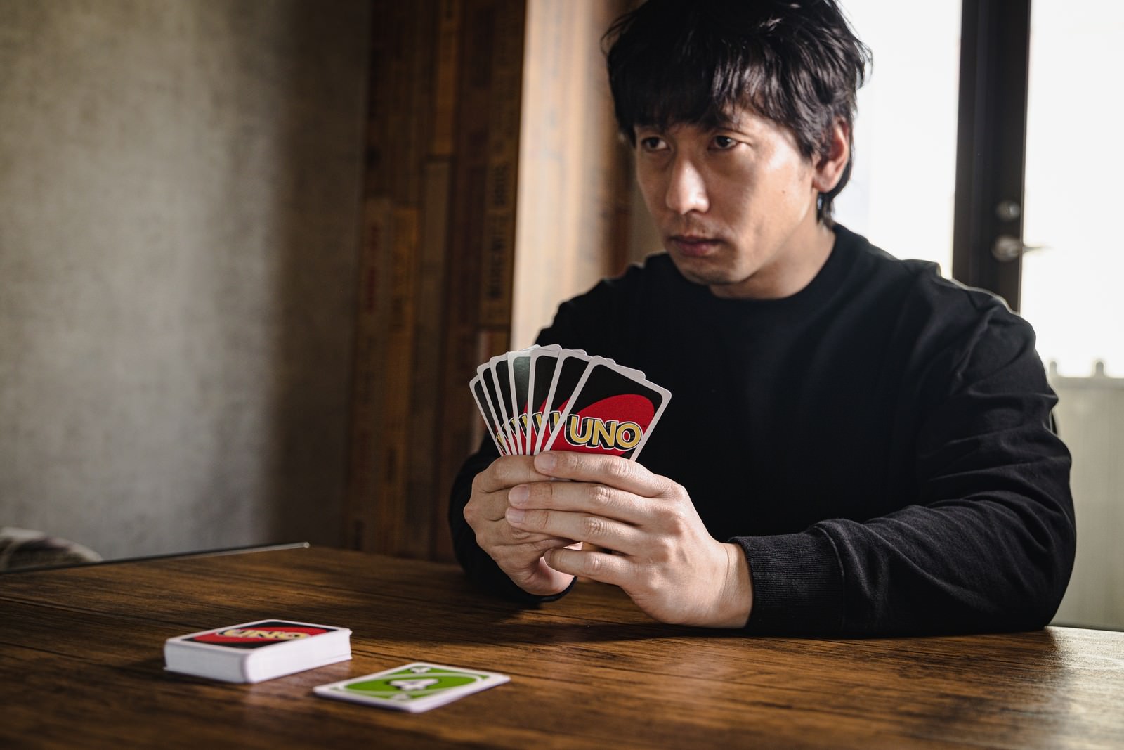 カードを手に持ち真剣な表情でゲームに集中する黒いシャツの男性
