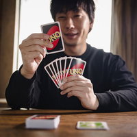 目的のカードを引いて思わずにんまりするウノ初心者男性の写真