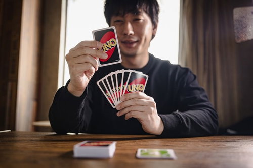 目的のカードを引いて思わずにんまりするウノ初心者男性