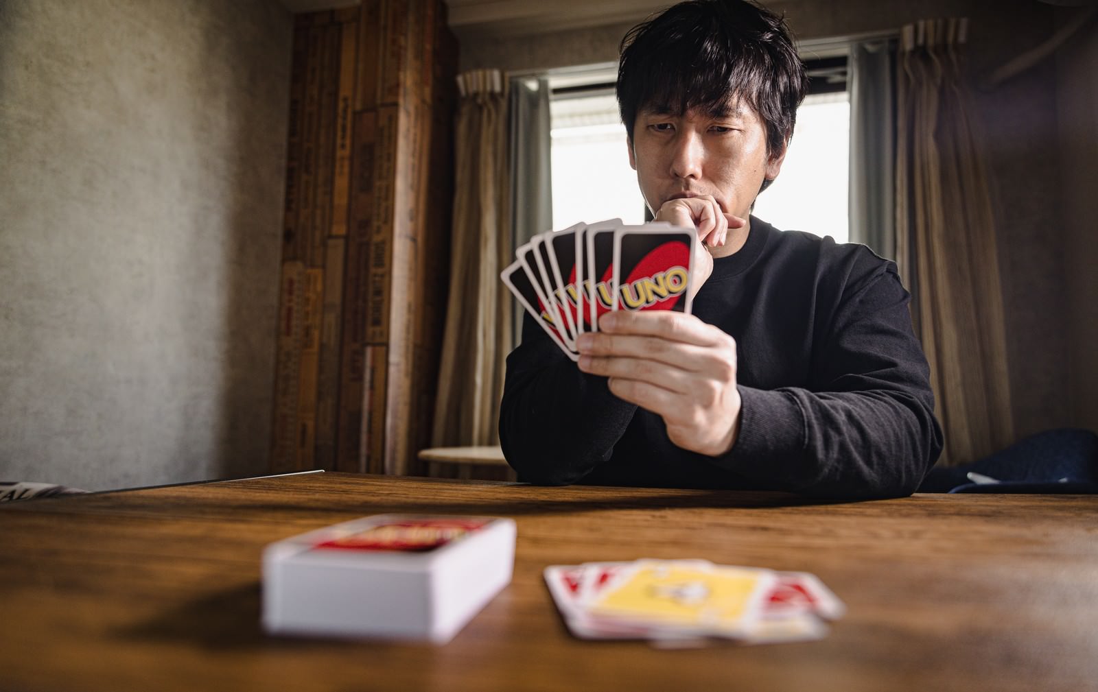カードを手に持ち次の一手を真剣に考える男性プレイヤー［モデル：大川竜弥］