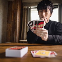 次の一手を考えるカードゲームのプレイヤー男性の写真