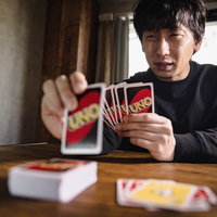 感情が顔に出やすいゲーム初心者、ウノの手札を持つ男性の写真