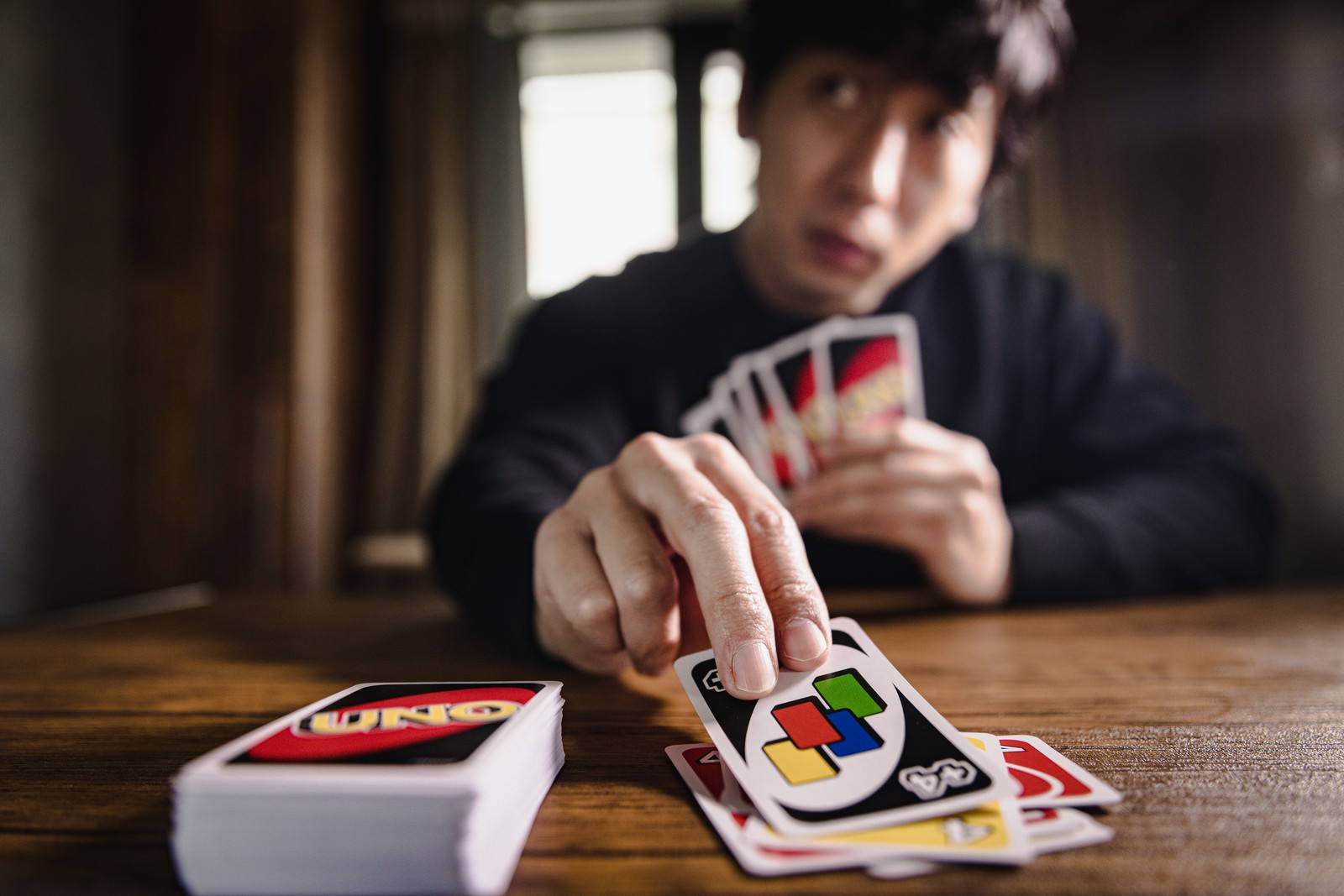 UNOのワイルドドロー4カードを手に持つ男性プレイヤー［モデル：大川竜弥］