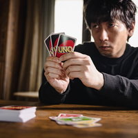 ウノで対戦相手を威圧する男性のカードゲーム対戦シーンの写真