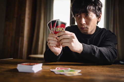 ウノで対戦相手を威圧する男性のカードゲーム対戦シーン