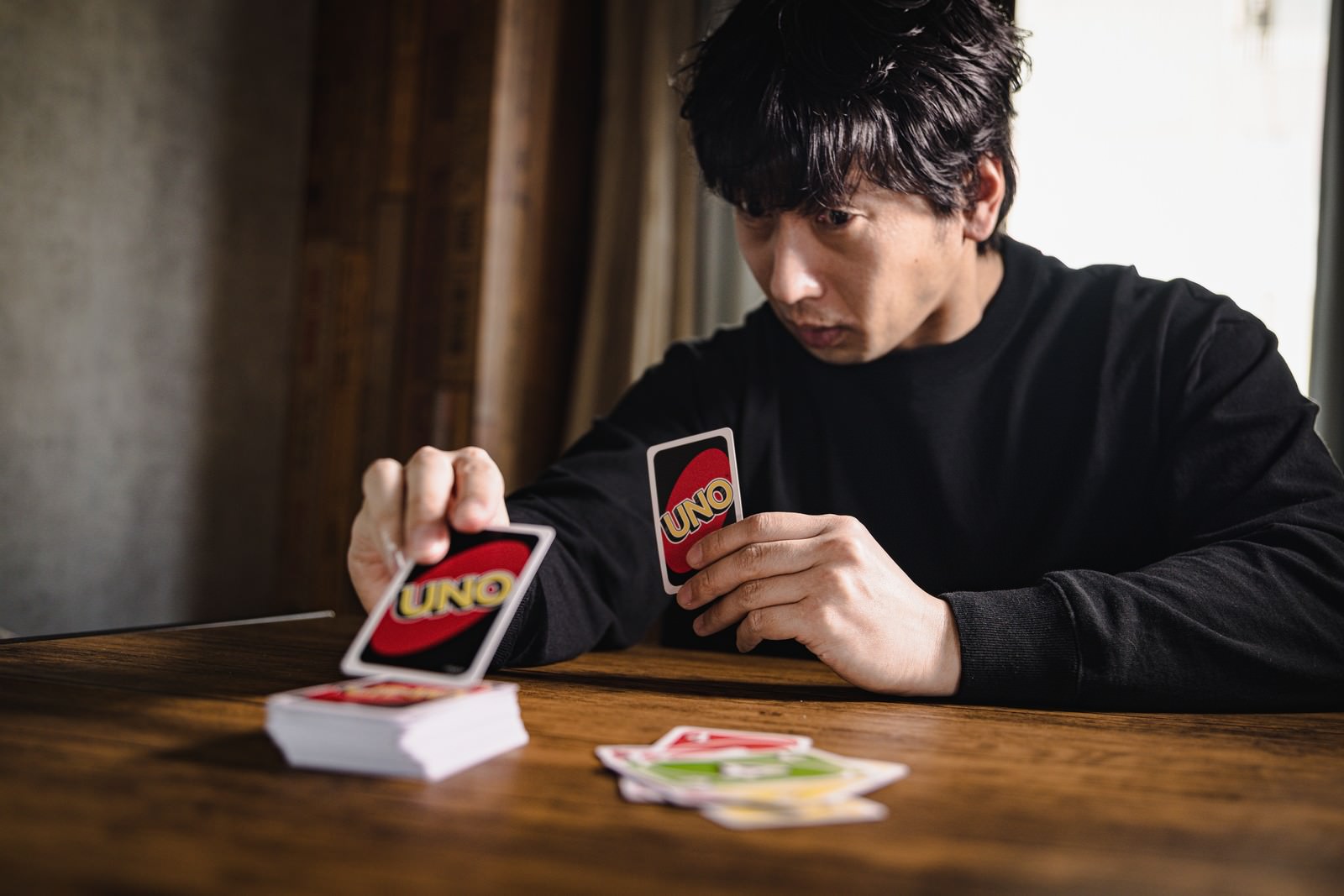 テーブルでカードゲームをする男性が手札を確認している様子［モデル：大川竜弥］