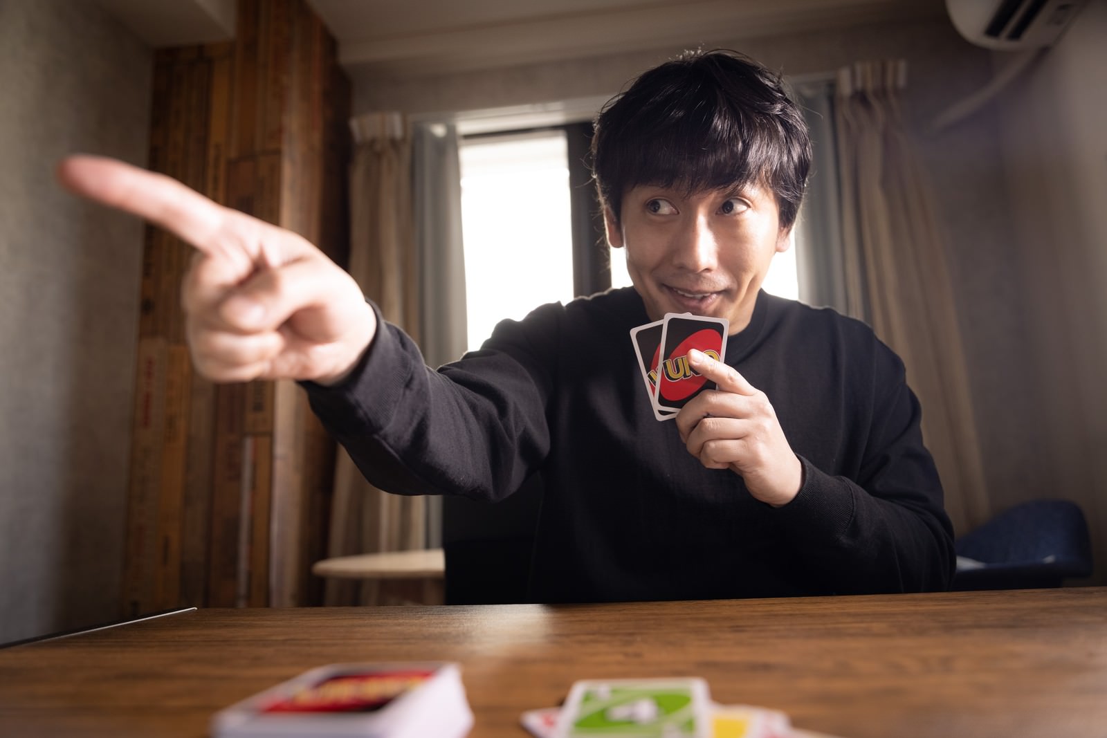 UNOの宣言ミスを指摘する男性が指差しをしている［モデル：大川竜弥］