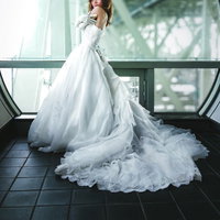 大きな窓の前で佇むウェディングドレス姿の女性の写真