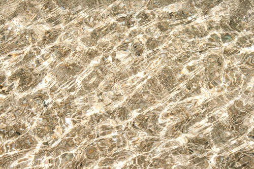 底の石や砂が見える透き通った水面のクローズアップ