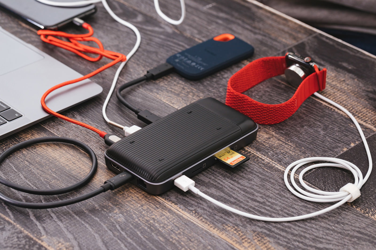 木製デスクに置かれた赤いモバイルバッテリーとUSB-Cハブ