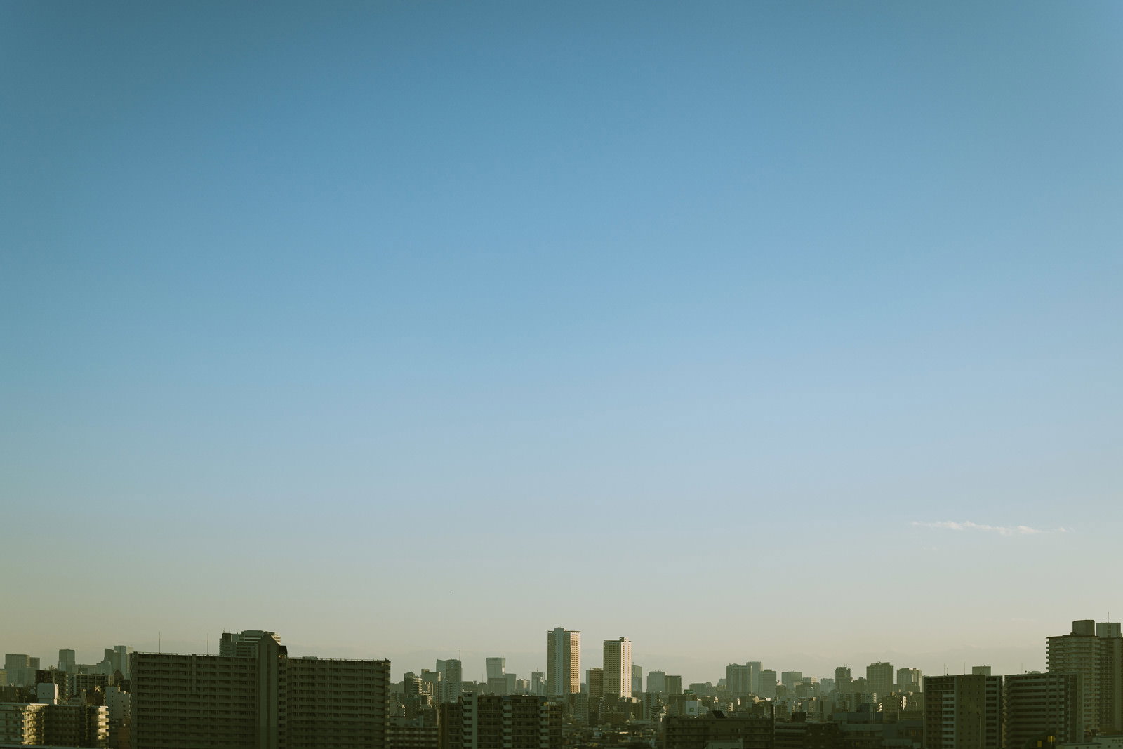 複数のマンションが地平線に連なり、快晴の青空に映える都市景観
