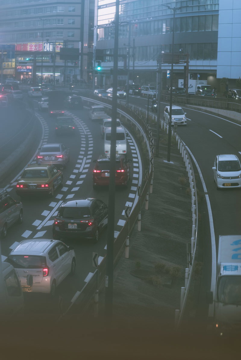 信号待ちで交差点に並ぶ複数の車のブレーキライトが点灯している渋滞時の風景