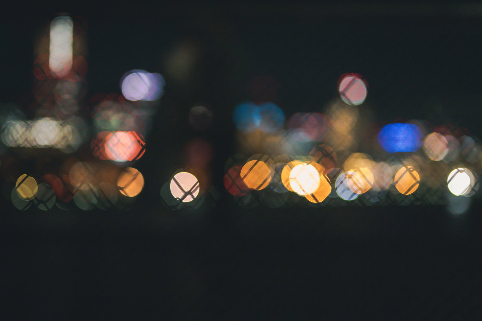フェンス越しに見える街の灯りが丸いボケとなって輝く夜景