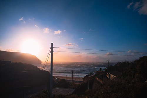 日が沈む神津島の海岸に寄せる荒波と夕焼けの風景