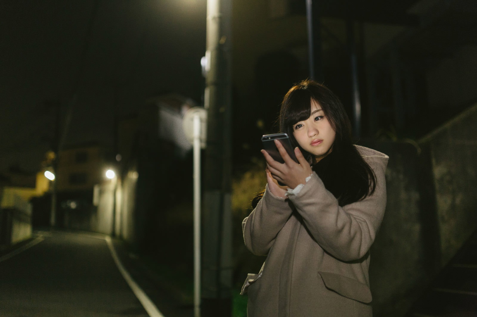 夜道でスマホを見ながら歩く女性［モデル：河村友歌］