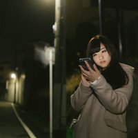 夜道でスマホに夢中になる女性の危険な歩きスマホの写真