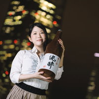 夜景を背景に一升瓶を持つ女性の飲み会イベント写真の写真