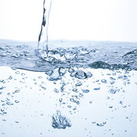 水槽の中の水の断面と注がれるミネラルウォーターの写真