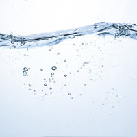 ミネラルウォーターの水面に広がる波と気泡の断面の写真