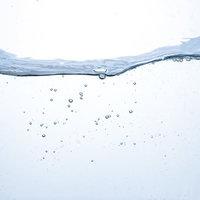 水槽の中の波と気泡が浮かぶ清涼な水中のミネラルウォーターの写真