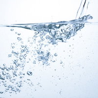 グラスに注がれるミネラルウォーターと沈む気泡の写真