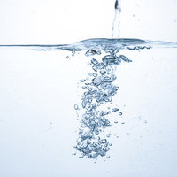 透明な水槽に注がれた水と舞い上がる気泡の飛沫の写真