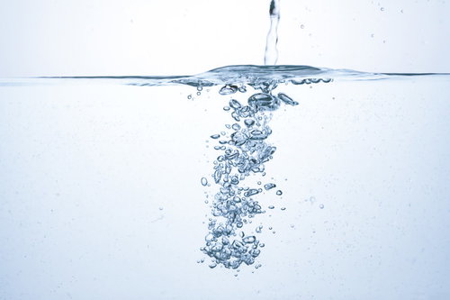 透明な水槽に注がれた水と舞い上がる気泡の飛沫